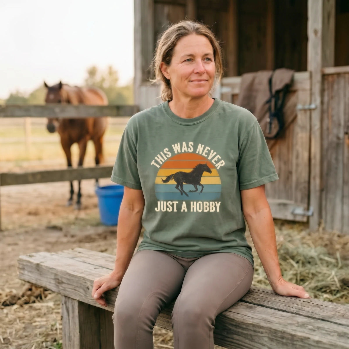 A rider sitting outside a tack room wearing a This Was Never Just a Hobby tee.