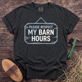 Respect My Barn Hours T-Shirt in Black, front view on a wooden barn surface. [color: Black]